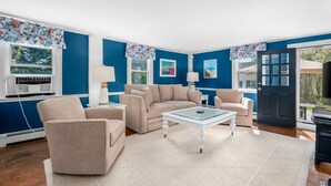 Un salon aux murs bleus, avec des meubles de couleur beige et une table basse en verre.