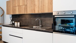 Eine moderne Küche mit Holzschränken, einer Spüle aus Edelstahl und einem eingebauten Backofen.