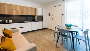 Eine moderne Küche mit Holzschränken, einem Backofen und einem Essbereich mit Tisch und Stühlen.