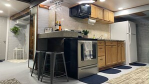 A modern kitchen with a central island, stainless steel appliances, wooden cabinets, and a built-in microwave. - `The Hideaway` Modern Apartment w/Sauna and Grill (Troy)