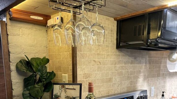 A kitchen with a marble countertop, a built-in oven, and a hanging wine rack. - `The Hideaway` Modern Apartment w/Sauna and Grill (Troy)