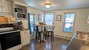 A kitchen with a stove, microwave, and sink. There are two chairs around a small table. - Hershey Music Box 2 - Duplex near HersheyPark, Giant Center, Hershey, Palmyra (Hummelstown)