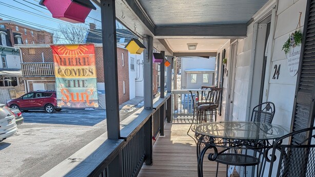 A wooden deck with a metal railing, a glass table with chairs, and a view of the street. - Hershey Music Box 2 - Duplex near HersheyPark, Giant Center, Hershey, Palmyra (Hummelstown)