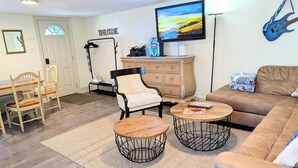A living room with a sofa, two round coffee tables, a chair, a TV, a guitar, and a dresser. - Hershey Music Box 2 - Duplex near HersheyPark, Giant Center, Hershey, Palmyra (Hummelstown)