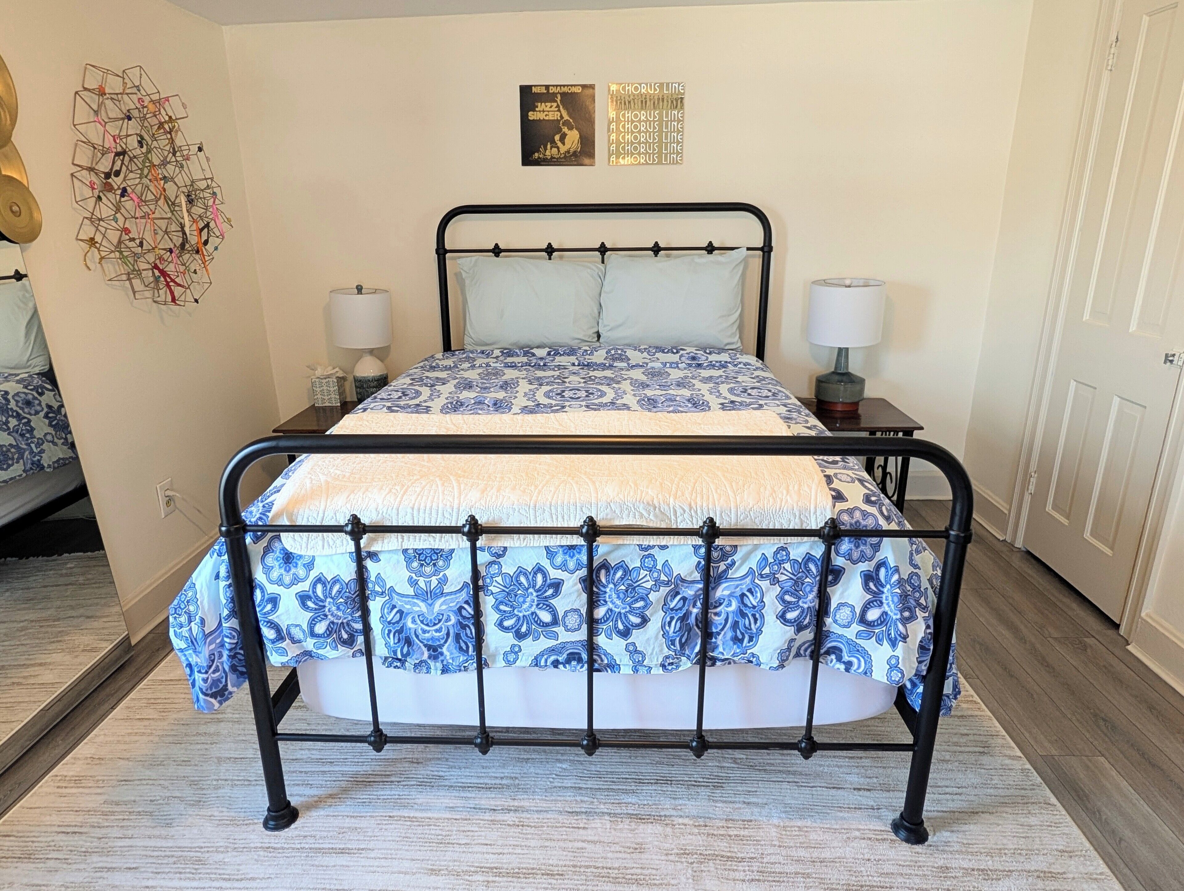 A bed with a metal frame, two bedside tables, a wall with a poster, and a door.