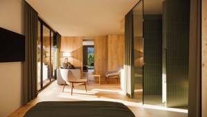 A modern bedroom with a large bed, a sitting area with a sofa and chairs, and a view of the outdoors through large windows. - Alma Alpina Lodge (Nova Ponente)