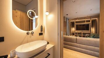 A modern bathroom with a large oval sink, a mirror with a circular light, and a wooden vanity.