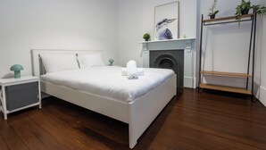 Une chambre à coucher comprenant un lit, une table de chevet, une cheminée et une étagère.