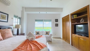 A bedroom with a bed, a TV, and a view of the outdoors.
