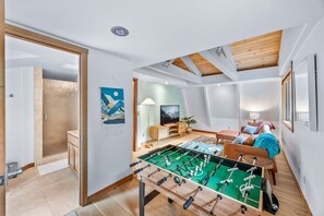 Um quarto amplo com mesa de pebolim, sofá e televisão.