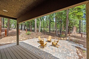 Ein überdachter Außenbereich mit Adirondack-Stühlen, umgeben von einer bewaldeten Landschaft.