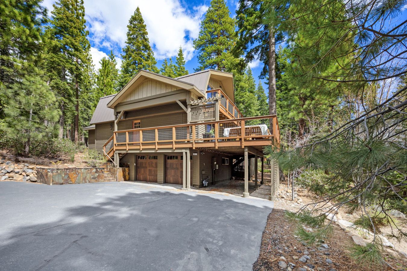 A two-story log cabin with a balcony, garage, and a driveway.