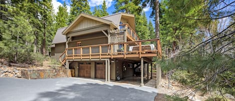 A two-story log cabin with a balcony, garage, and a driveway.