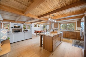 A spacious kitchen with wooden cabinets, a large island, and a stone fireplace. - Tahoe Getaway Home-Close to Beach and hiking (Kings Beach)