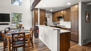 Una cocina moderna con armarios de madera, una isla central y un comedor con mesa y sillas.