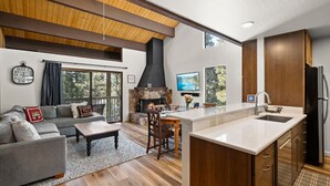 Una sala de estar moderna con chimenea, un comedor y una cocina con gabinetes de madera y una isla grande.