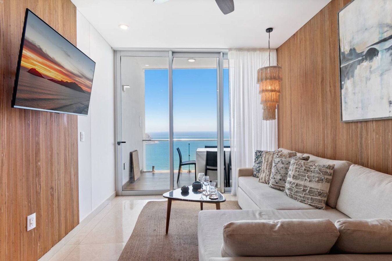 A modern living room with a sofa, a coffee table, and a TV mounted on the wall.