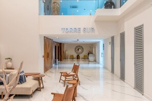 Eine geräumige Lobby mit hoher Decke, einer zentralen Sitzecke mit Stühlen und einer Couch, und einem Schild mit der Aufschrift 'TORRE SUR'.