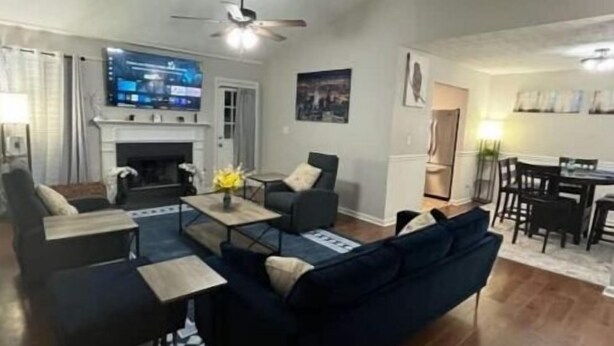 A living room with a dark blue sofa, a fireplace, a television, and a dining area with a table and chairs. - The Good Life Place in Smyrna (Smyrna)