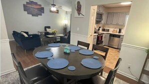 A dining area with a round table, dark chairs, and blue placemats. There is a ceiling light fixture above the table. - The Good Life Place in Smyrna (Smyrna)