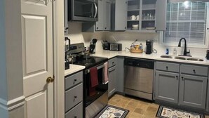A compact kitchen with grey cabinets, a microwave, a dishwasher, and a sink. - The Good Life Place in Smyrna (Smyrna)