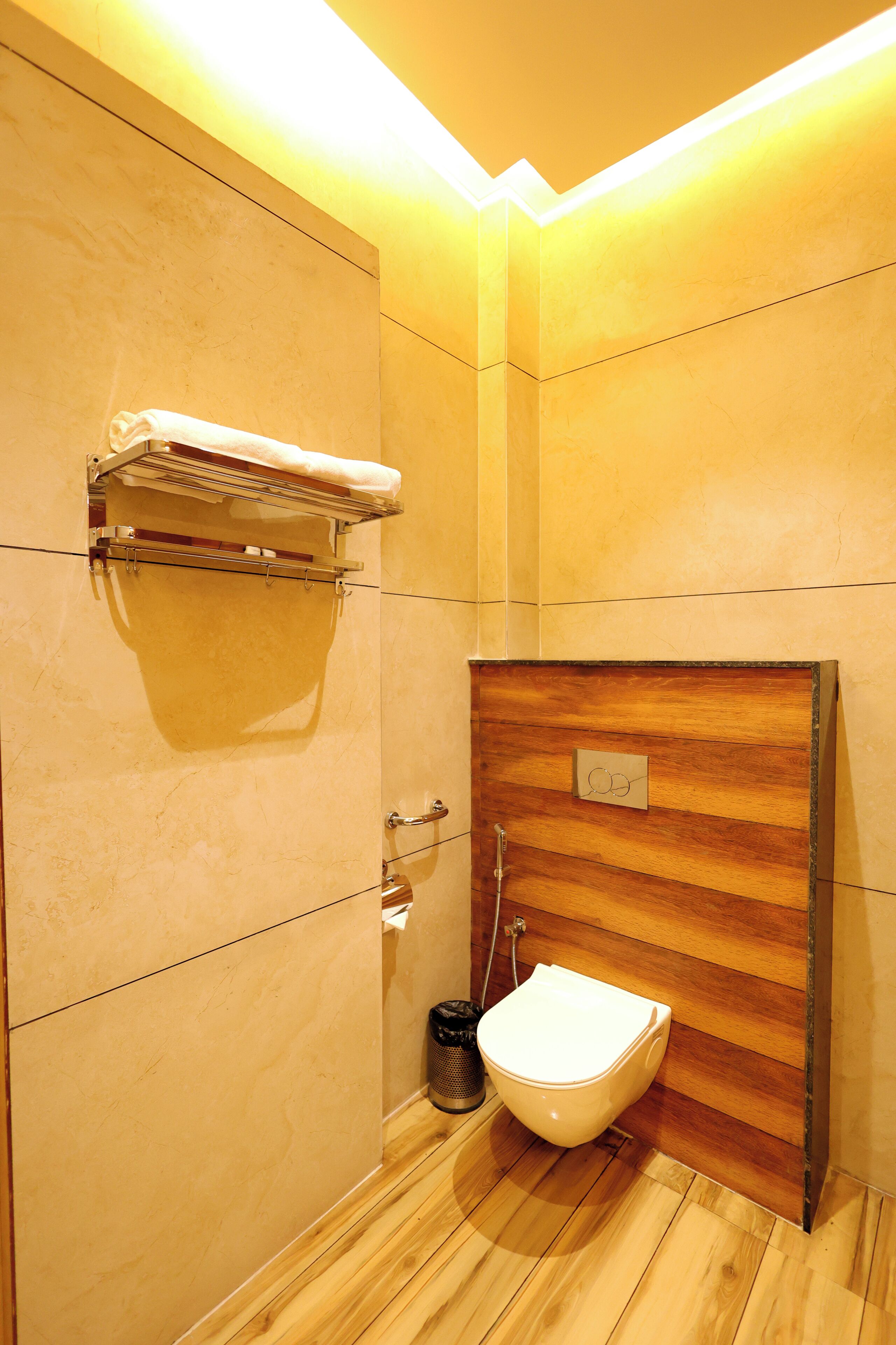 Ein modernes Badezimmer mit einem Holzbadezimmerhocker, einer weißen Toilette und einem Handtuchhalter.