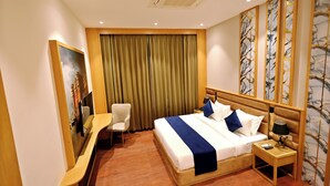 Ein Hotelzimmer mit einem Bett, einem Schreibtisch, einem Sessel, einem Nachttisch und einem Bild an der Wand.