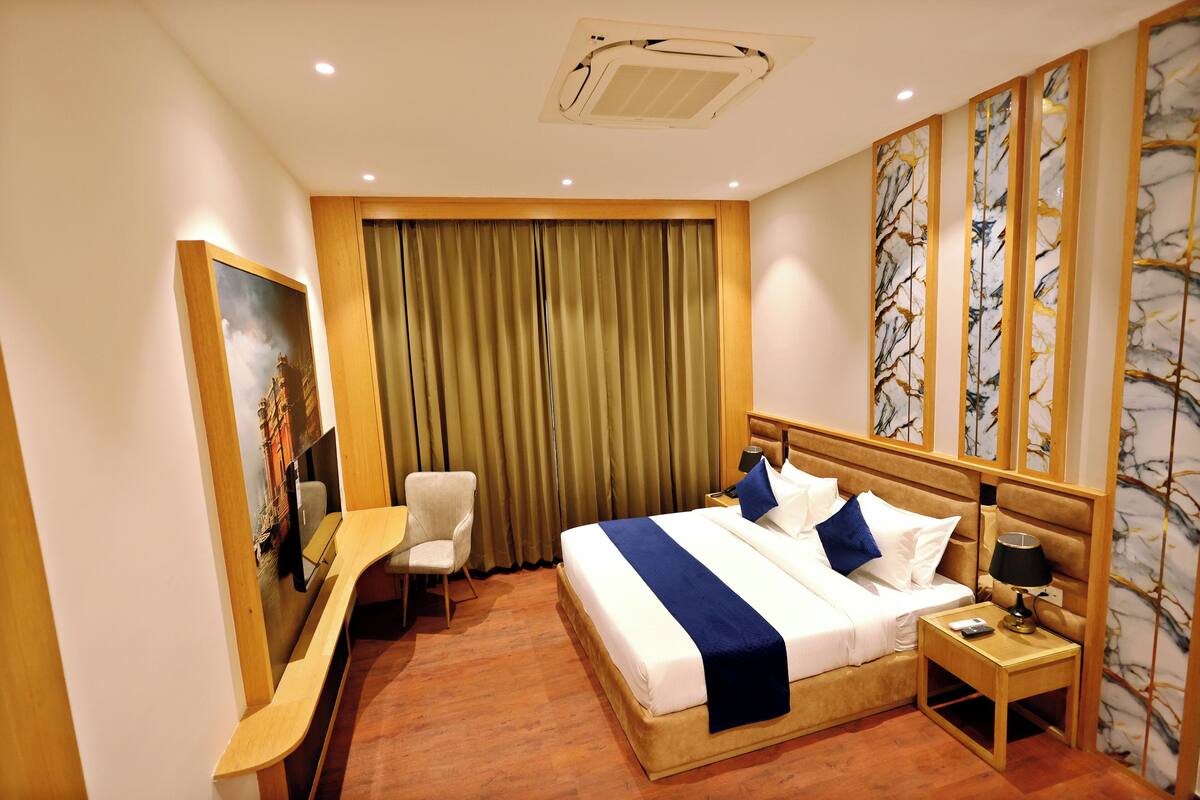Habitación de hotel con cama, escritorio, silla, mesita de noche y un cuadro en la pared.