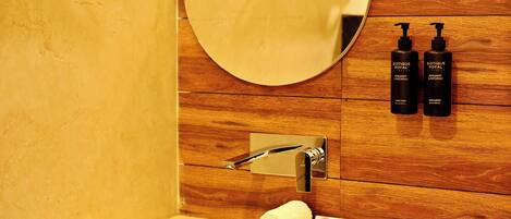 Un baño con un lavamanos blanco, un espejo redondo y dos botellas de jabón de manos Biotique Royal.