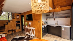 Une cuisine moderne avec des meubles en bois, une cuisinière encastrée et un évier. On y trouve un coin repas avec une table et des chaises en bois, ainsi qu’une grande fenêtre donnant sur l’extérieur.
