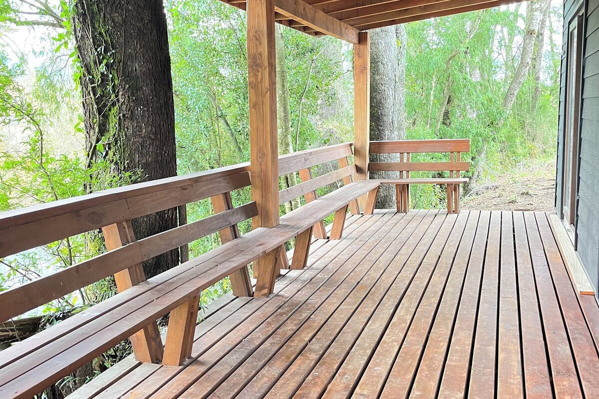 A wooden deck with benches and a view of a forested area.