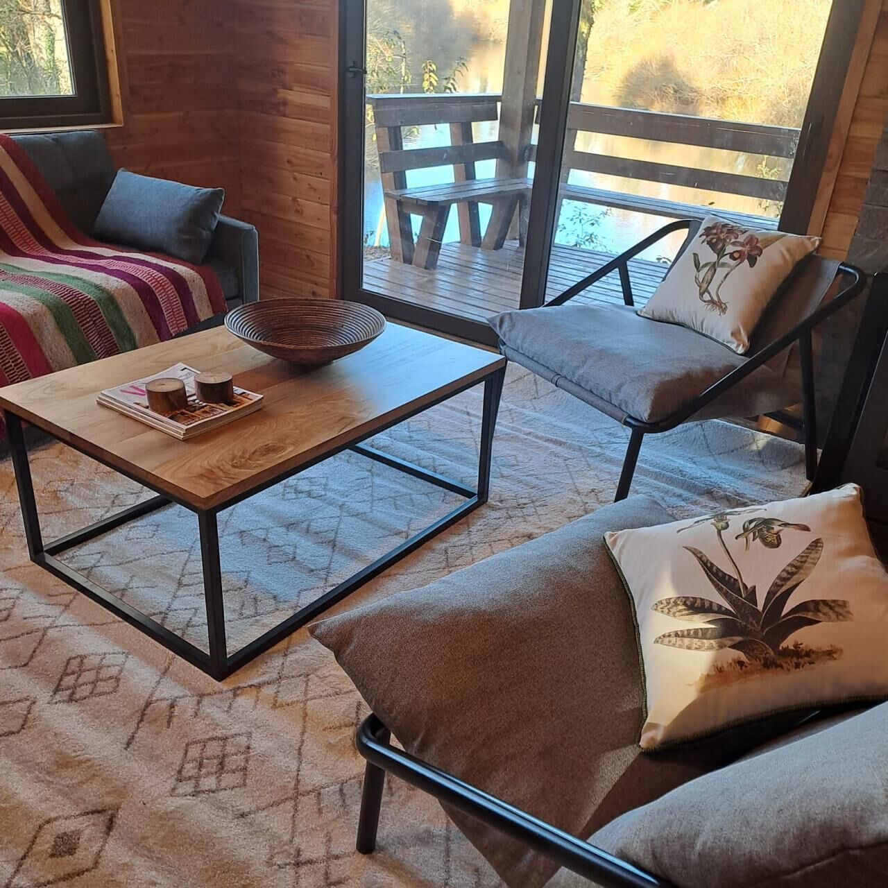 Un coin salon confortable avec une table basse en bois, des canapés moelleux et une vue sur une terrasse extérieure.