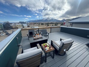Una terraza con mobiliario exterior, una parrilla y vistas a montañas.