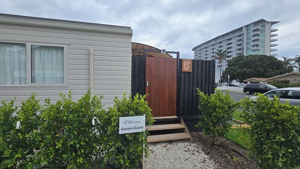 A mobile home with a wooden door and a sign reading "Keriu Guest." - Orewa Kiwi Cabins - Kereru Cabin (Orewa)