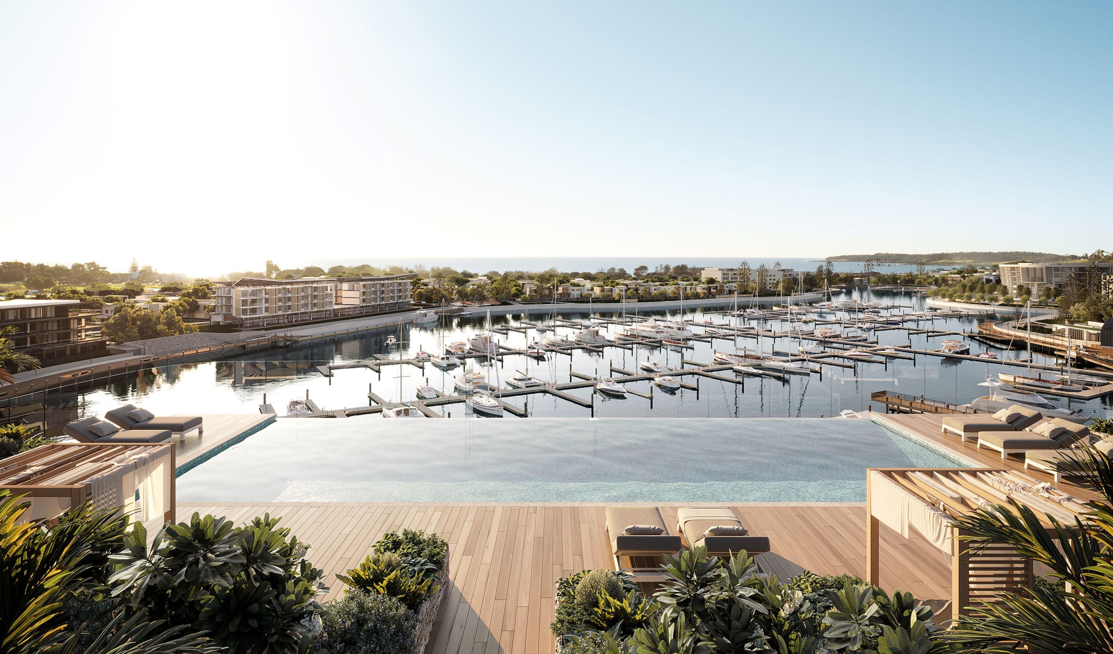 A marina with numerous boats docked, a large swimming pool, and lounge areas with sunbeds.