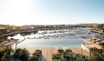 A marina with numerous boats docked, a large swimming pool, and lounge areas with sunbeds.
