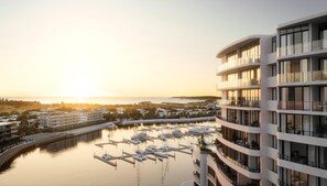 A modern hotel with multiple balconies overlooking a marina with boats. - Crowne Plaza Shell Cove Marina (Wollongong)