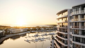 A modern hotel with multiple balconies overlooking a marina with boats.