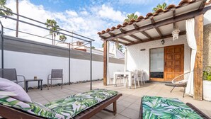 Un patio con dos sillones, una mesa y una zona de estar cubierta con una puerta de madera.