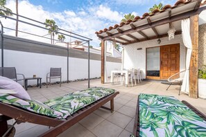 Un patio con dos sillones, una mesa y una zona de estar cubierta con una puerta de madera.