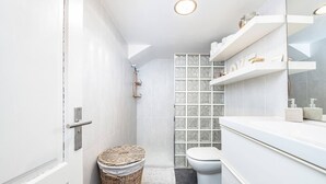 Un baño moderno con tocador blanco, cabina de ducha de vidrio y inodoro blanco.