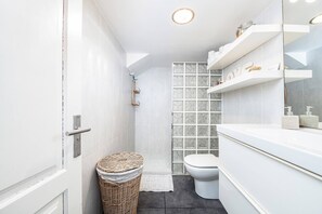 Un baño moderno con tocador blanco, cabina de ducha de vidrio y inodoro blanco.