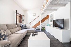 Uma sala de estar moderna com sofá, mesa de centro, televisão e escada.