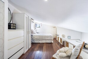 Un dormitorio con cama, cómoda, espejo, ventana y zona de escritorio.