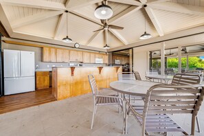 Una cocina amplia con armarios de madera, una isla central con asientos y un comedor con sillas de metal y una mesa.