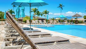 Un área junto a la piscina con sillones de descanso y sombrillas.