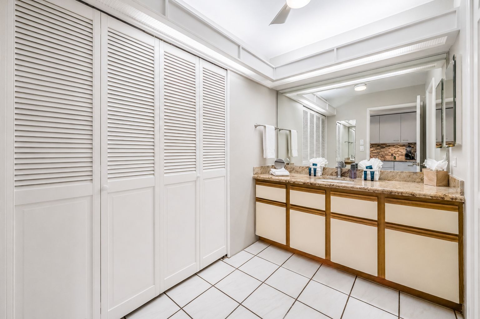 A modern bathroom with a vanity, mirror, and storage cabinets.