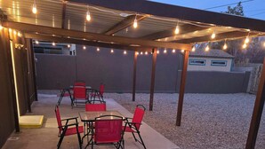 An outdoor patio with a covered seating area, string lights, and a gravel ground. - "Breaking Bad !"  Neighborhood -3-bedroom house  Albuquerque with WiFi, AC (Albuquerque)