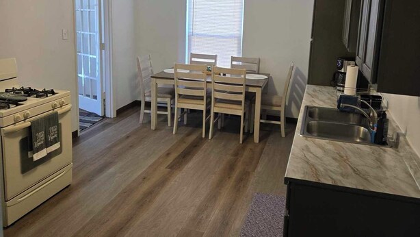A compact kitchen with a gas stove, a ceiling fan, a dining table with chairs, and a window with blinds. - "Breaking Bad !"  Neighborhood -3-bedroom house  Albuquerque with WiFi, AC (Albuquerque)