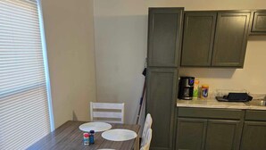 A dining area with a wooden table and white chairs, a kitchen with green cabinets, and a window with blinds. - "Breaking Bad !"  Neighborhood -3-bedroom house  Albuquerque with WiFi, AC (Albuquerque)